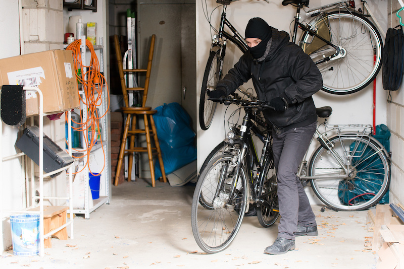 A man steals a bicycle from a garage that had an open door